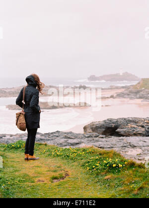 Eine Frau Lookng über die Felsen und die Küste an einem windigen Tag am Meer. Stockfoto