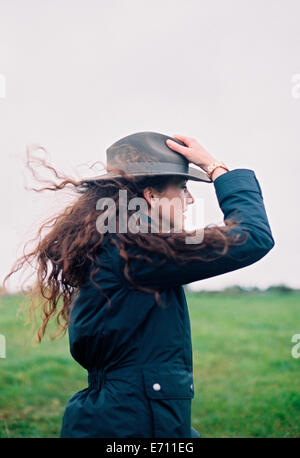 Eine Frau mit langen Haaren im Wind geblasen mit ihrem Hut. Stockfoto