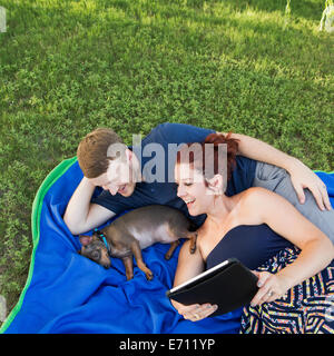 Ein paar auf einem blauen Teppich mit einem kleinen Hund. Eine Frau mit einem digital-Tablette. Stockfoto