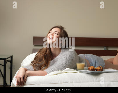 Schöne junge Frau lachend auf Hotelbett Stockfoto