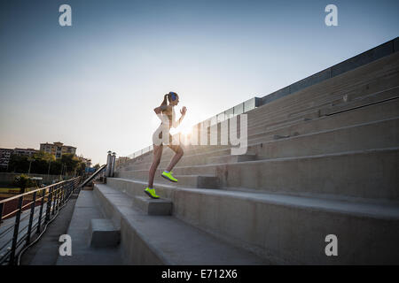 Junge Frau, die Treppe hinauf läuft Stockfoto