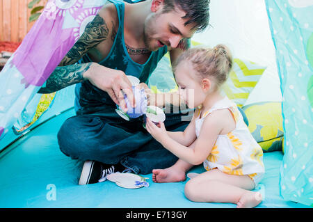 Junger Mann und Kleinkind Tochter spielt mit Teetasse im Zelt Stockfoto