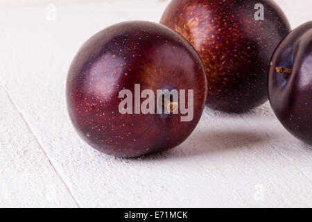 Frische reife rote saftige appetitliche Pflaume Nahaufnahme mit Stiel, die vor der Kamera in ein Konzept für eine gesunde Ernährung und Diät mit Stockfoto