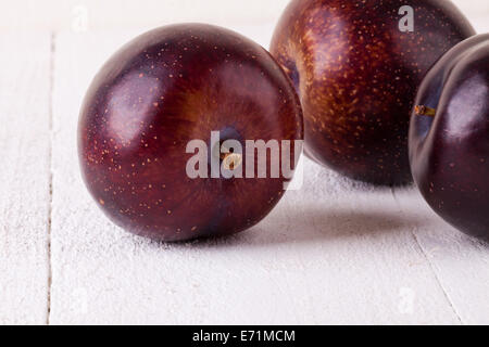 Frische reife rote saftige appetitliche Pflaume Nahaufnahme mit Stiel, die vor der Kamera in ein Konzept für eine gesunde Ernährung und Diät mit Stockfoto