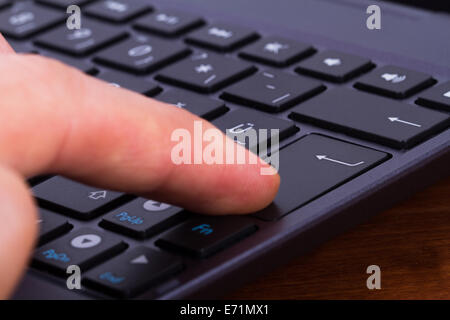 Nahaufnahme des Zeigefinger drücken enter-Taste auf der Laptop-Tastatur. Stockfoto