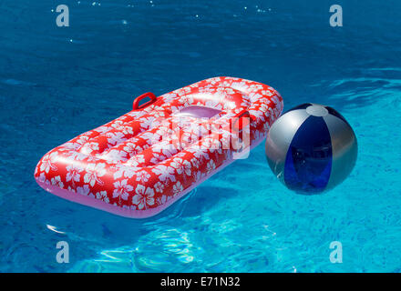 Luftmatratze und Wasserball im Pool Stockfoto