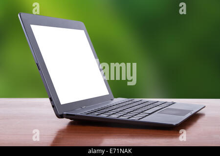 Tablet-Laptop mit weißen leeren Bildschirm auf Holztisch, Seitenansicht, grünen natürlichen Hintergrund. Stockfoto