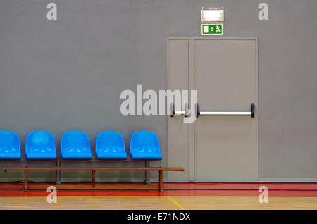 Fluchttür neben einer Reihe von blau sitzt in einer Sporthalle Stockfoto