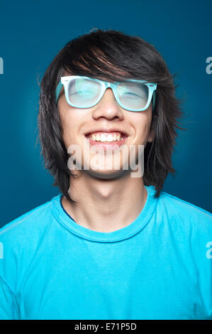 Porträt eines lächelnden glücklich Hipster jungen asiatischen Mannes mit Brille hautnah. Blaue Farben Stockfoto