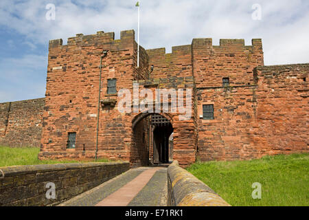 Historischen Carlisle Castle mit imposanten roten Sandsteinmauern, Eingang mit Fallgitter und grasigen Graben unter blauem Himmel Stockfoto