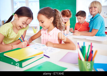 Zwei SchülerInnen zeichnen in Gruppe auf Grund von Klassenkameraden Stockfoto