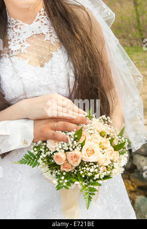 Hände und Ringe auf Hochzeit Bouquet. Stockfoto