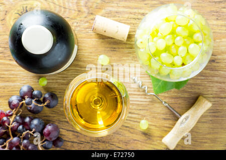 Glas Weißwein, eine Flasche Rotwein und Haufen von Trauben, Flaschenöffner, Kork. Die Draufsicht. Stockfoto