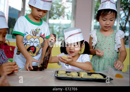 Hefei, China Anhui Provinz. 4. September 2014. Kinder benutzen Werkzeuge, Mooncakes in Hefei, Hauptstadt der ostchinesischen Provinz Anhui, 4. September 2014 machen. Das Mid-Autumn Festival, das am 8. September dieses Jahres fällt, ist ein traditionelles chinesisches fest für Familientreffen, während die Leute der Vollmond zusammen genießen und Essen Mondkuchen - kleine Runde Kuchen mit verschiedenen Füllungen. © Liu Junxi/Xinhua/Alamy Live-Nachrichten Stockfoto