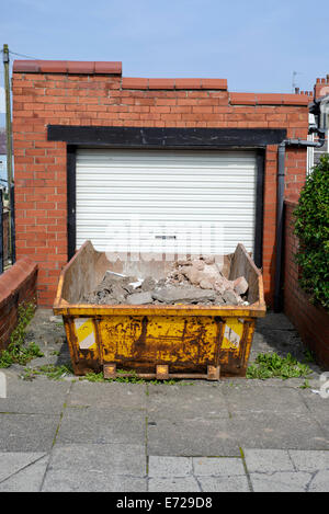 Mit Bauherren Schutt außerhalb einer Garage in Blackpool, Lancashire, überspringen Stockfoto