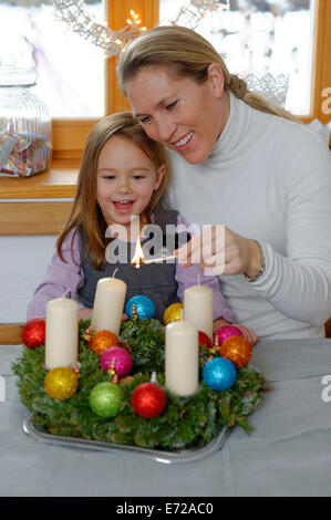 Mutter und Tochter Beleuchtung die erste Kerze auf dem Adventskranz, erster Sonntag im Advent Stockfoto