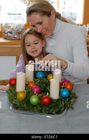 Mutter und Tochter Beleuchtung die erste Kerze auf dem Adventskranz, erster Sonntag im Advent Stockfoto