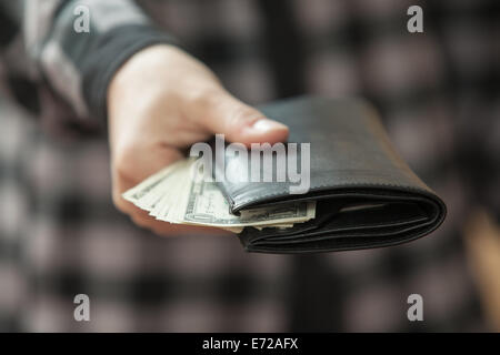 Des Mannes Hand, die eine schwarze Geldbörse mit Geld Stockfoto