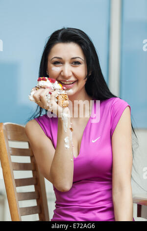 Schönes Mädchen essen einen Stück Kuchen mit Sahne bestrichen Stockfoto