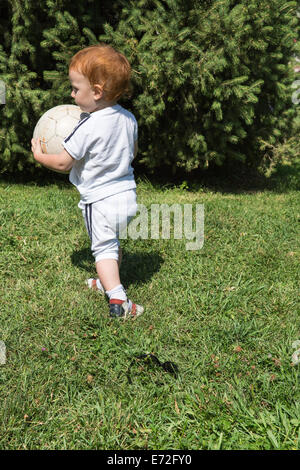 Entzückende kleine Kind Junge mit Fußball im Park an der Natur im Sommer. Verwenden Sie es für Baby, Elternschaft oder Liebe Konzept Stockfoto