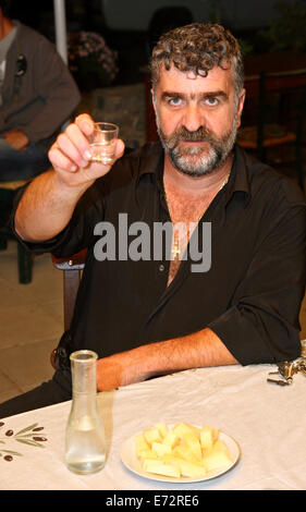 "Cheers" von einem kretischen Mann mit Raki (oder "Tsikoudia"), das traditionelle Getränk Kretas. Im Karidi Village, Lassithi, Griechenland. Stockfoto