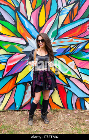 Blick auf junge junge Frau gegen Graffiti an Wand Stockfoto