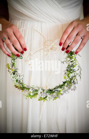 Junge Braut hält Kranz aus Blumen Stockfoto