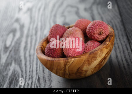 Reife Litschis in Holz Schüssel auf alten Eichentisch Stockfoto