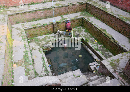 Nepalesische Frauen füllen Sie Wasser in Tank für den Einsatz und trinken am heiligen Teich am 2. November 2013 in Patan Nepal Stockfoto