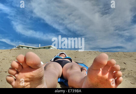 Caorle, Veneto, Italien. Mai 2014, Vorfrühling Seazon am Adria-Strand in Caorle Resort. Junge Dame legt am Sandstrand Stockfoto