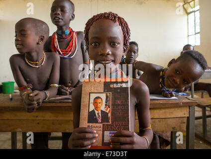 Hamer Stamm Mädchen hält ein Buch mit Barack Obama auf dem Cover In einer Schule, Turmi, Omo-Tal, Äthiopien Stockfoto