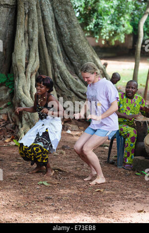 Afrika, Benin, Ouidah. Lokale Frau tanzt mit Touristen während Voodoo Tanz vor Iroko Baum in Kpasse heiligen Wald. Stockfoto