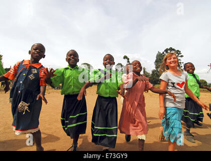 Kenia, Kakamega, Gruppe von schwarzen und weißen Kinder springen fröhlich im Schulhof (MR). Stockfoto