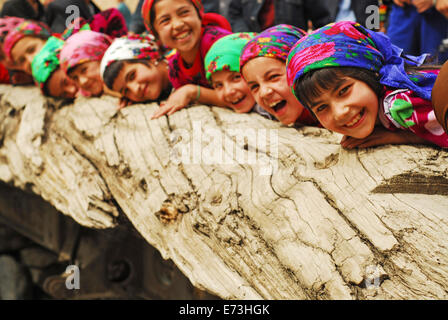 Tadschikistan, Penjakent, Gruppe von einheimischen Mädchen in traditioneller Tracht posiert und spielt am Fluss auf Holzbrücke. Stockfoto