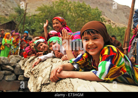 Tadschikistan, Penjakent, Gruppe von einheimischen Mädchen in traditioneller Tracht posiert und spielt am Fluss auf Holzbrücke. Stockfoto