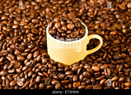 Tasse mit Kaffeebohnen auf Kaffeebohne Hintergrund gefüllt Stockfoto