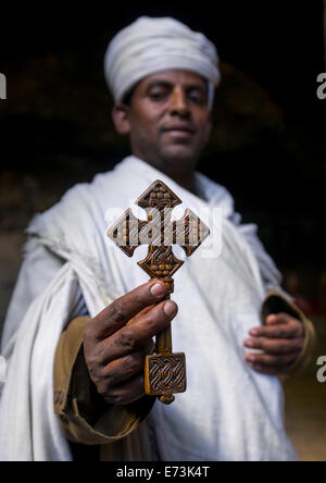 Priester hält ein Kreuz innen Yemrehana Krestos Felsenkirche, Lalibela, Äthiopien Stockfoto