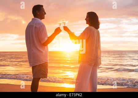 Glücklich romantische älteres Paar Glas Champagner bei Sonnenuntergang am Strand genießen Stockfoto