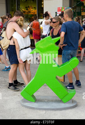 Deutschland, Berlin, Mitte, junge Menschen auf dem Bürgersteig neben einer großen grünen Modell eines Ampelmann oder nachberufliche man. Stockfoto