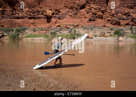 Canyonlands National Park, Utah - Flussführer Julian Springer trägt eine aufblasbare Stand up Paddleboard während einer Floßfahrt Stockfoto