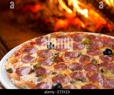 Traditionelle Pizza mit Salami, Kapern und Oliven im Ofen backen Stockfoto