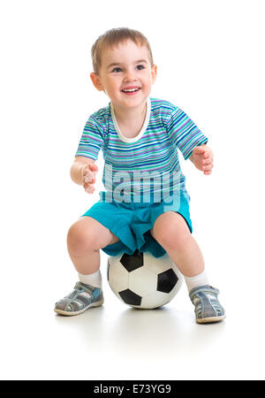 Kleiner Junge sitzt auf Fußball isoliert auf weiss Stockfoto