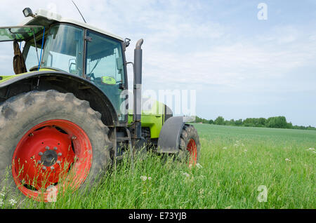 Saison der Bereich Arbeit Baumaschinen Traktor steht in Wiese Stockfoto