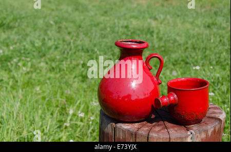 Nahaufnahme von zwei Keramik rot Wasserkrug und Schale auf Baumstumpf Natur Hintergrund Stockfoto