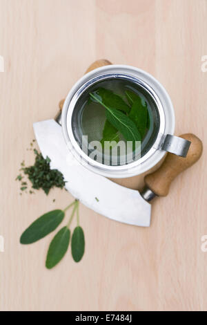 Salvia Officinalis. Salbeitee und Salbeiblätter auf einem Holzbrett. Stockfoto
