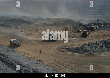 Hitatchi und CAT Muldenkipper warten geladen werden, während man Weg voller Felsen in einer massiven Tagebau Kupfer-Mine in Sambia fährt. Stockfoto