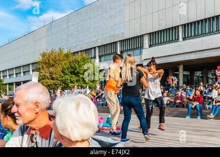 Moskau, Russland. Samstag, 6. September 2014. Der Tag der Stadt Moskau wird jährlich in den ersten Samstag im September gefeiert. Die Stadt wurde 1147 von Prinz Yuri Dolgorukiy (Long-handed) gegründet. In diesem Jahr feiert die Stadt 867th Geburtstag. Faire und Freizeit Festivalgelände im Museon Park der Künste. Nicht identifizierte Zuschauer von der musikalischen Darbietung. Junge Männer und Frauen tanzen auf einem Holzdeck. Zentralen Haus der Künstler Galerie Gebäude im Hintergrund. Bildnachweis: Alex Bilder/Alamy Live-Nachrichten Stockfoto