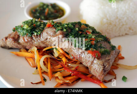 Fleisch mit Chimichurri serviert auf einem Bett aus Gemüse und Reis in einem Restaurant. Stockfoto