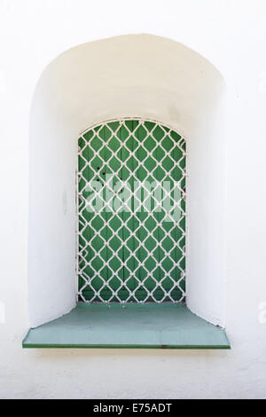Weiße Wand und grünes Fenster mit Gitter, Hintergrundtextur Stockfoto