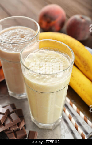 Banane Smoothie im Glas mit frischen Früchten und Schokolade auf hölzernen Hintergrund Stockfoto